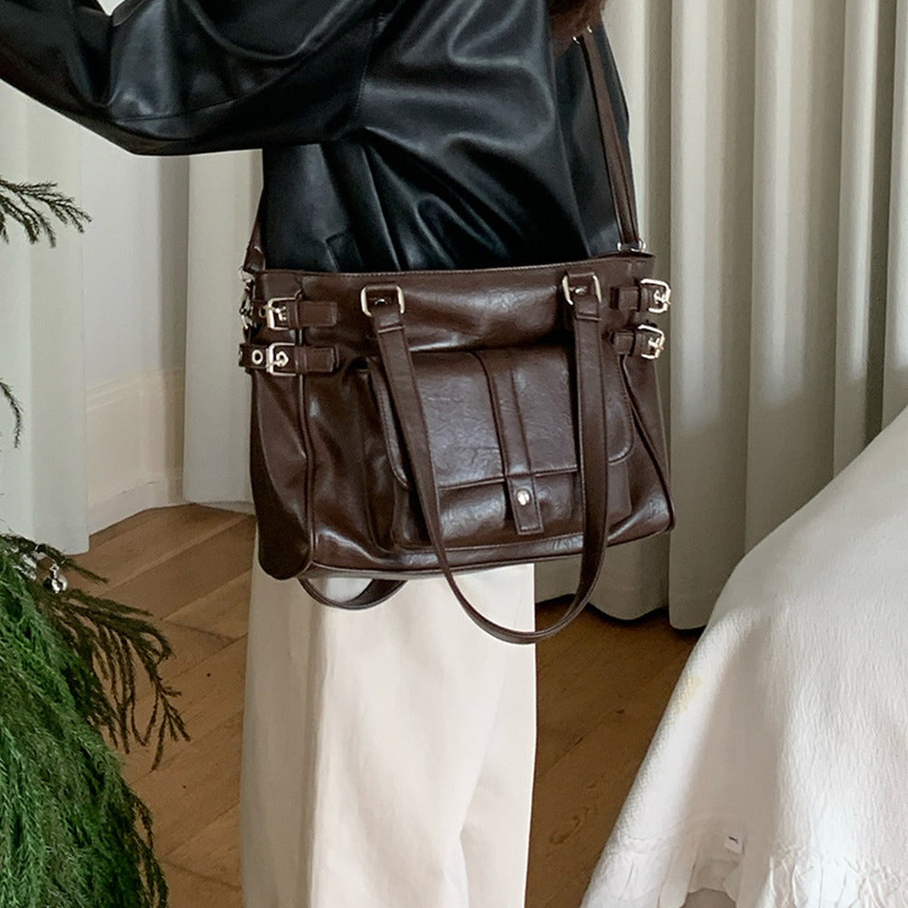 Coffee brown tote bag with silver side buckles worn with a leather jacket