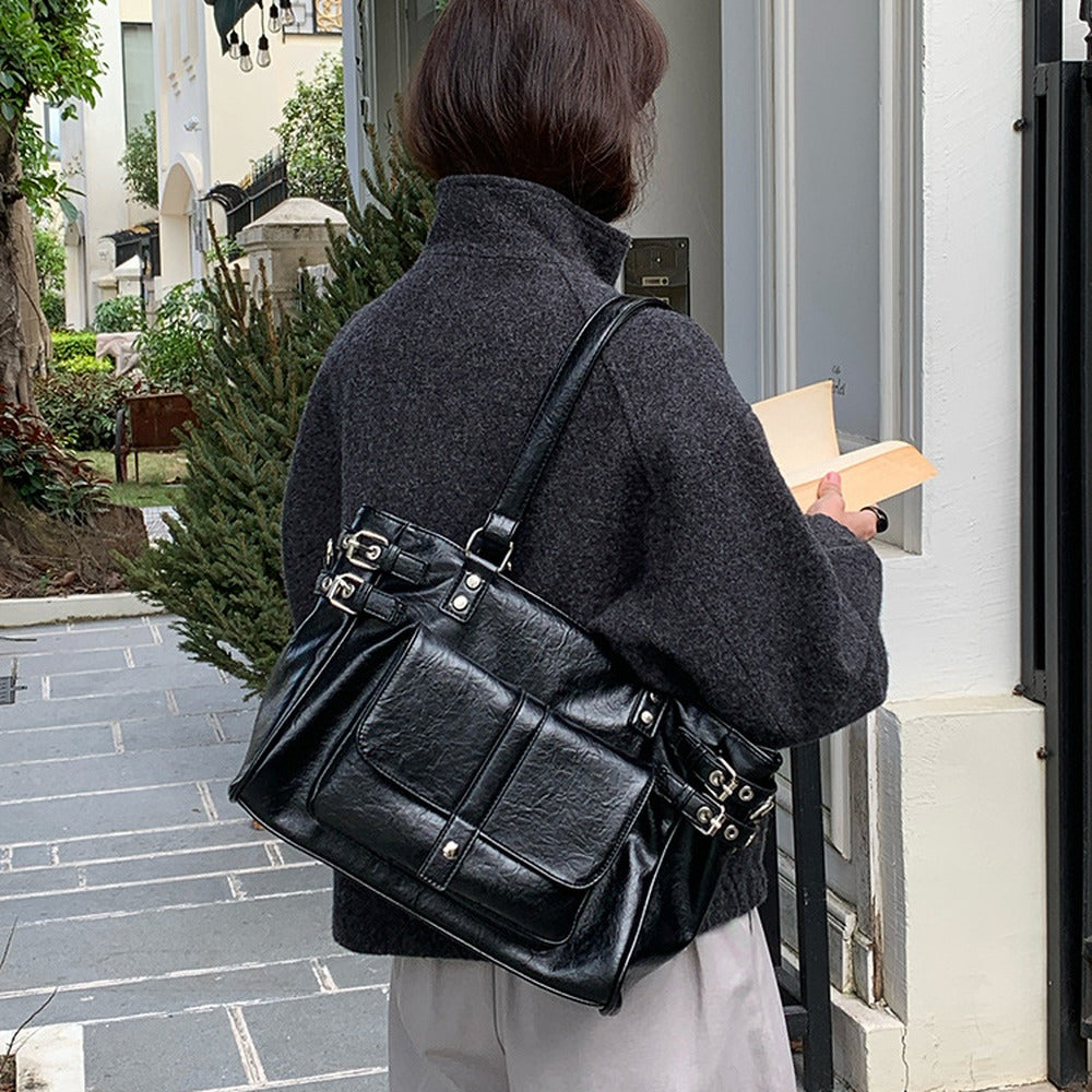 Black vintage buckle tote bag worn over a grey coat
