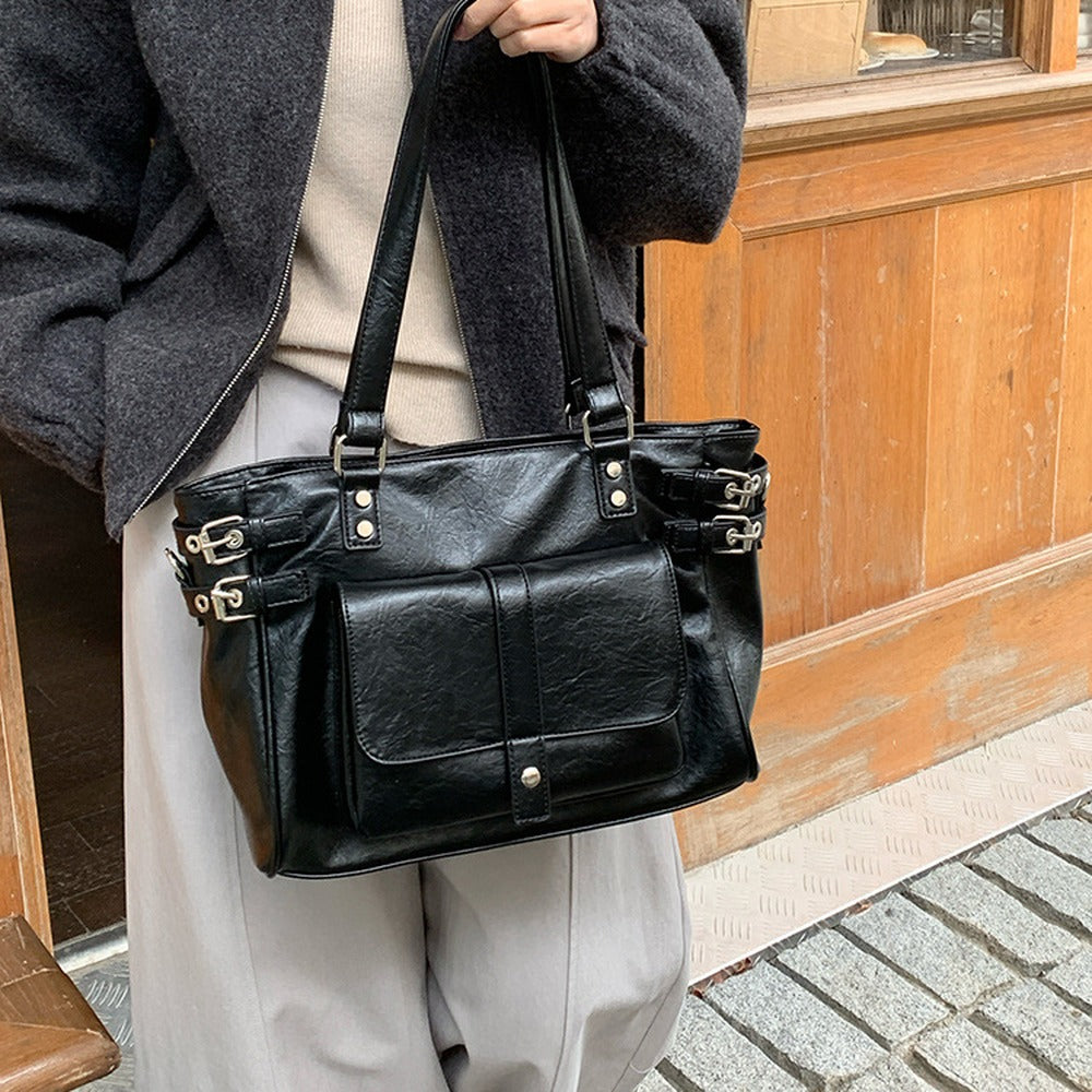 Black faux leather tote with front flap pocket carried on the shoulder