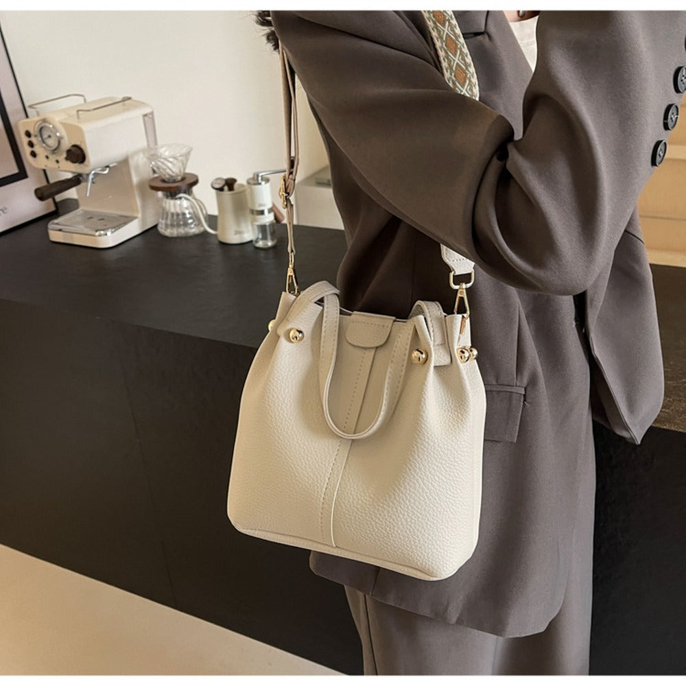 Cream bucket bag worn crossbody with wide strap