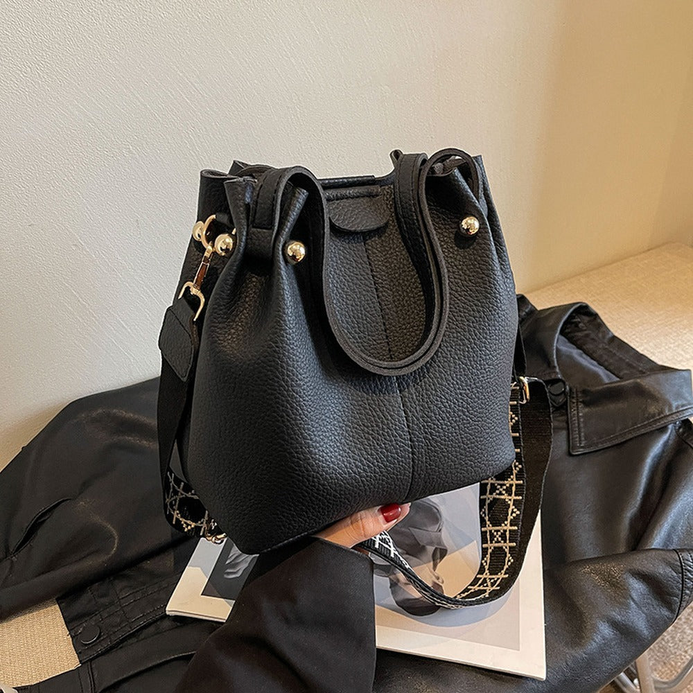 Black bucket bag with top handles and wide crossbody strap